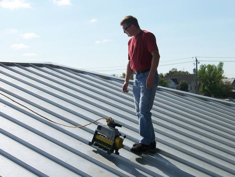 Local roofer operating a seaming machine to join standing-seam metal roof panels