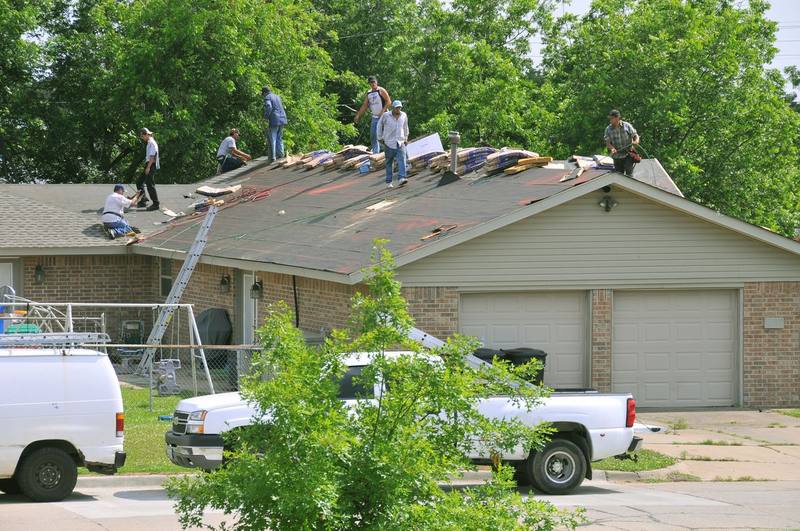 Local roofing crew replacing storm-damaged shingles on a residential roof