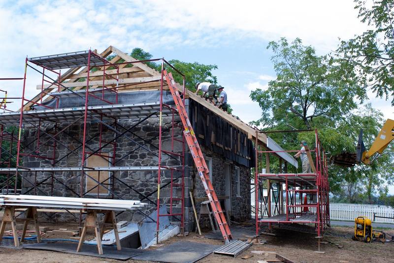 Local roofing crew installing new wood shingles on a roof during a restoration project