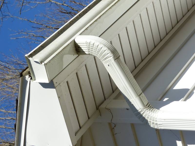 Seamless aluminum gutter run and downspout elbow along a residential roofline