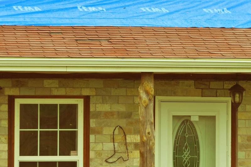 Blue tarp secured over a tornado-damaged home's roof