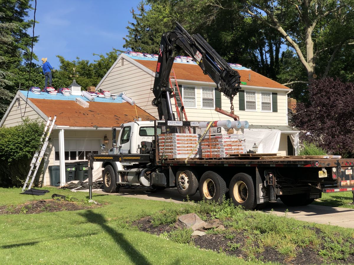 Construction crew replacing the roofing and gutters on a residential home