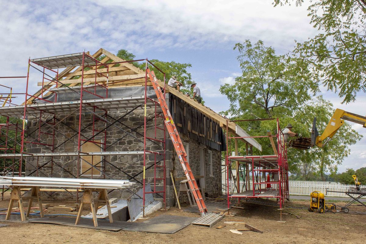 Roofers pausing while installing new wood shingles on a roof during restoration work